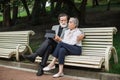 Senior couple relaxing on bench and using tablet Royalty Free Stock Photo