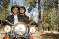 Senior couple riding motorcycle through a forest