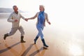 Senior Couple Running Along Winter Beach Royalty Free Stock Photo