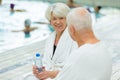 senior couple sat talking poolside Royalty Free Stock Photo