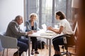 Senior Couple Signing Document In Meeting With Female Financial Advisor In Office Royalty Free Stock Photo