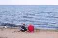 Senior couple sitting on the beach on a picnic with fishing rods by the sea during the day