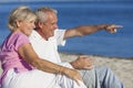 Senior Couple Sitting on Beach Pointing Royalty Free Stock Photo