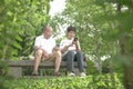 Senior couple sitting on bench, reading their phones in the park Royalty Free Stock Photo