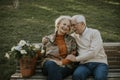 Senior couple sitting on the benchwith basket full of flowers and embracing Royalty Free Stock Photo