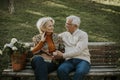 Senior couple sitting on the benchwith basket full of flowers and embracing Royalty Free Stock Photo