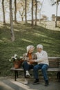 Senior couple sitting on the benchwith basket full of flowers and embracing Royalty Free Stock Photo