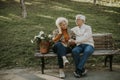 Senior couple sitting on the benchwith basket full of flowers and embracing Royalty Free Stock Photo