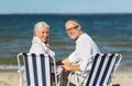 Senior couple sitting on chairs at summer beach Royalty Free Stock Photo