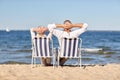 Senior couple sitting on chairs at summer beach Royalty Free Stock Photo