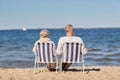 Senior couple sitting on chairs at summer beach Royalty Free Stock Photo