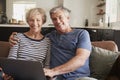 Senior couple sitting on couch use laptop, smiling to camera Royalty Free Stock Photo