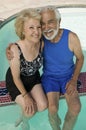 Senior Couple sitting on edge of swimming pool elevated view portrait. Royalty Free Stock Photo