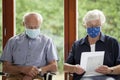 Senior couple sitting with face masks in a bright waiting room of a hospital