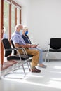 Senior couple sitting with face masks in a bright waiting room of  a hospital or an office Royalty Free Stock Photo