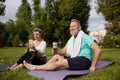 Senior couple sitting on fitness mats rest after yoga training outdoors in park Royalty Free Stock Photo