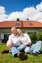 Senior couple sitting in front of their home Royalty Free Stock Photo