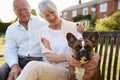 Senior Couple Sitting On Garden Bench With Pet French Bulldog Royalty Free Stock Photo