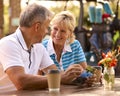 Senior Couple Sitting Having Coffee After Round Of Golf Looking At Score Card Together Royalty Free Stock Photo