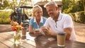Senior Couple Sitting Having Coffee After Round Of Golf Looking At Score Card Together Royalty Free Stock Photo