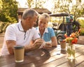 Senior Couple Sitting Having Coffee After Round Of Golf Looking At Score Card Together Royalty Free Stock Photo
