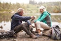 Senior couple sitting by a lake pouring coffee from a flask during a camping holiday, Lake District, UK Royalty Free Stock Photo