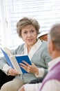 Senior couple sitting on living room couch reading Royalty Free Stock Photo