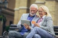 Senior couple sitting on bench and shopping on line with tablet and credit card Royalty Free Stock Photo