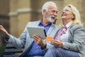 Senior couple sitting on bench and shopping on line with tablet and credit card Royalty Free Stock Photo