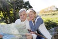 Senior couple sitting by river looking at map Royalty Free Stock Photo
