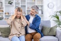 Senior couple sitting on sofa in living room, wife rubbing her head with hands, suffering from severe migraine headache Royalty Free Stock Photo