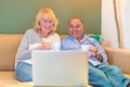 Senior couple sitting on sofa looking at laptop with two cups of coffee Royalty Free Stock Photo
