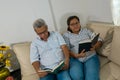 Senior couple sitting on sofa and reading a book in living room Royalty Free Stock Photo