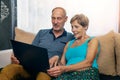 Senior couple sitting in sofa and using laptop together Royalty Free Stock Photo