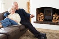 Senior Couple Sitting On Sofa Watching TV