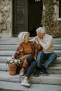 Senior couple sitting on stairs with basket full of flowers and groceries Royalty Free Stock Photo