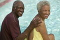 Senior Couple sitting by swimming pool portrait.