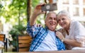 Senior couple sitting at a table in a cafe and using mobile phone Royalty Free Stock Photo