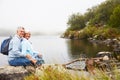 Senior couple sitting together by a lake, looking to camera Royalty Free Stock Photo