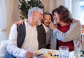 Senior couple with small granddaughter indoors at Christmas, having fun.