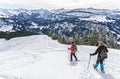 Senior couple is snowshoe hiking in alpine snow winter mountains. Allgau, Bavaria, Germany. Royalty Free Stock Photo