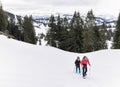 Senior couple is snowshoe hiking in alpine snow winter mountains. Allgau, Bavaria, Germany. Royalty Free Stock Photo