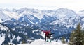 Senior couple is snowshoe hiking in alpine snow winter mountains panorama. Happy successful People with outstrechted