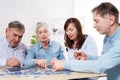 Senior couple solving jigsaw puzzle together with family at home Royalty Free Stock Photo