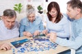 Senior couple solving jigsaw puzzle together with family at home Royalty Free Stock Photo