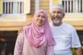 Senior couple standing in front of wooden house