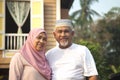 Senior couple standing in front of wooden house