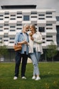Senior couple standing on a grass in summer with straw basket and flowers Royalty Free Stock Photo