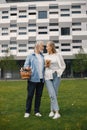 Senior couple standing on a grass in summer with straw basket and flowers Royalty Free Stock Photo