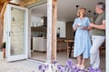 Senior Couple Standing And Looking Out Of Kitchen Door Drinking Coffee Royalty Free Stock Photo